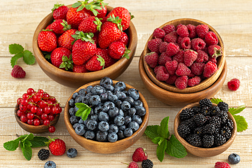 Fresh summer organic berries in wooden bowls, healthy food concept, selective focus
