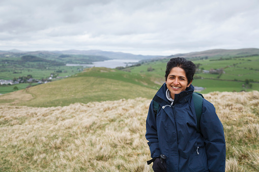 British Asian Indian woman in waterproof coat hiking in Snowdonia National Park near Lake Bala, North Wales, UK