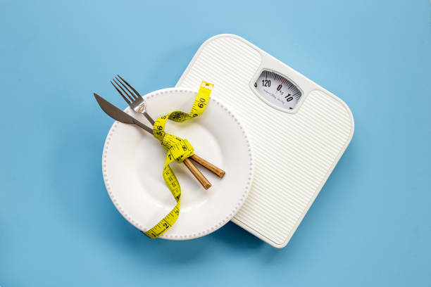 istock Weight scale and tape measure on dinner plate. Dieting and weight control concept 1466682040