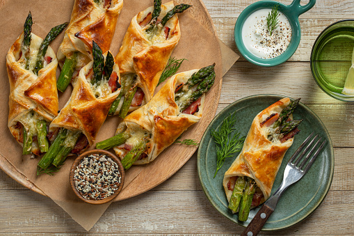 asparagus and bacon puff pastry bundles, top view, wooden background