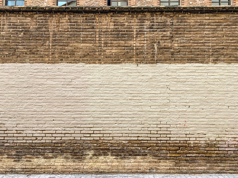 Front view of brick wall painted with beige color to cover graffitis