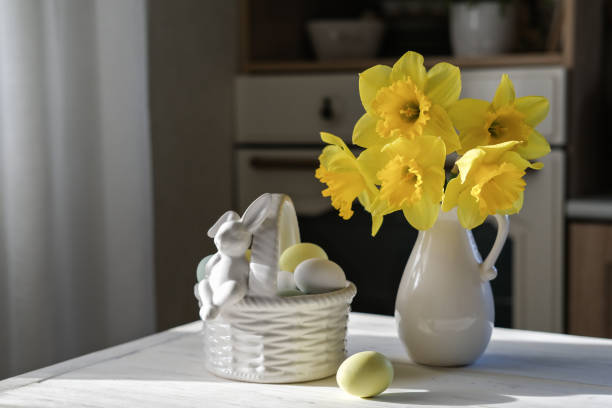 гнездо с яйцами в мягких пастельных тонах и ваза с нарциссами на кухонном столе. пасхальный натюрморт - daffodil flower yellow vase стоковые фото и изображения