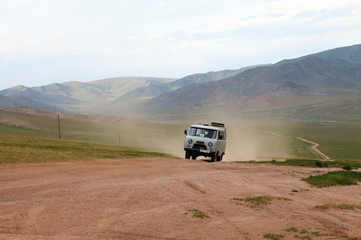 Van drives through dirt road at desert, Jargalant, Mongolia.