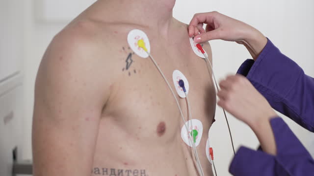 B-roll of nurse adjusting electrodes on a male patient's chest, preparing him for the Holter monitor