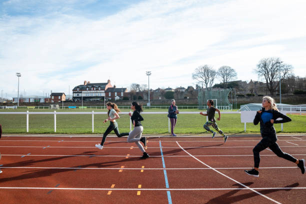 Track Training A shot of a diverse group of females training on a running track. It is a bright day with blue skies. There are no spectators in the frame. secondary school activities stock pictures, royalty-free photos & images