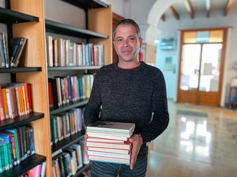 Librarian man holding books in library