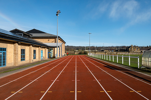 A shot of a running track within a sports facility. The track is empty on a bright sunny day.