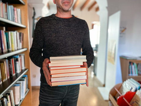Librarian man holding books in library