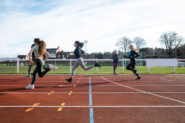 Training on the Track A side shot of a diverse group of females training on a running track. It is a bright day with blue skies. There are no spectators in the frame. secondary school activities stock pictures, royalty-free photos & images