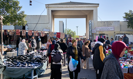 Sousse, Tunisia, January 15, 2023: Entrance to the Sunday market in Sousse with many women and stalls selling shoes