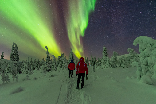 Two people looking at the northern lights in the winter landscape of Lapland