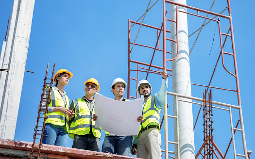 Civil engineer or supervisor inspects and directs workers on a building construction site.