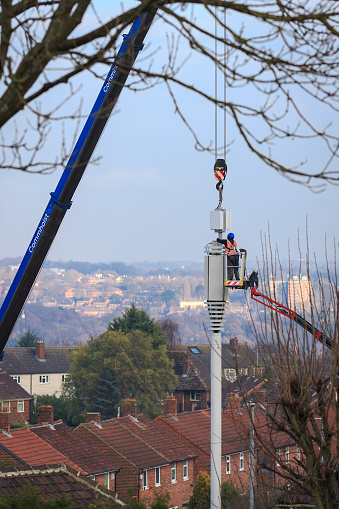 Engineer working from a cherry picker, installing a 5G tower in an urban area of Leeds, United Kingdom. December 13th, 2022.