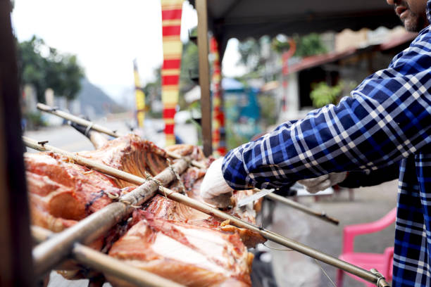 Man cooking a piglet on a outdoors wooden spit in the Sierra del Escambray, Escambray Mountains, a mountain range with caves, rivers, waterfalls, and canyons in central  Cuba, in the provinces of Sancti Spíritus, Cienfuegos and Villa Clara.
