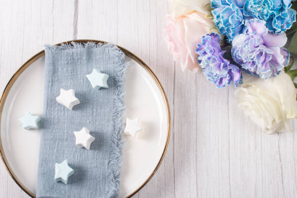 istock An empty white ceramic plate with a blue napkin and a blue carnation. Copy space, banner 1466715064
