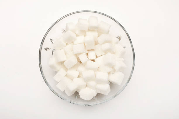 High angle view sugar cubes in a glass bowl on the white background