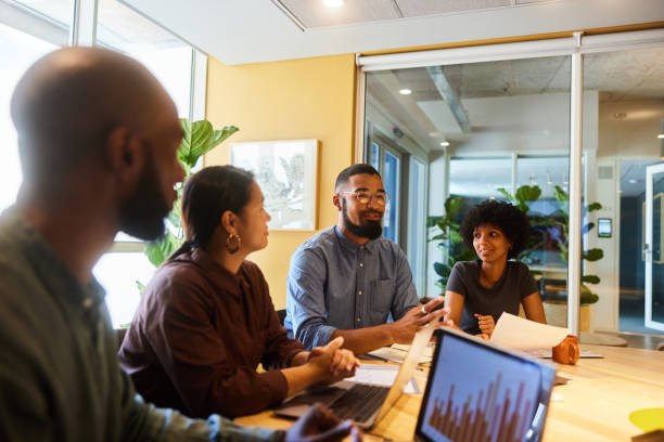 istock Diverse businesspeople smiling while disucssing graphs during a board room meeting 1466717962