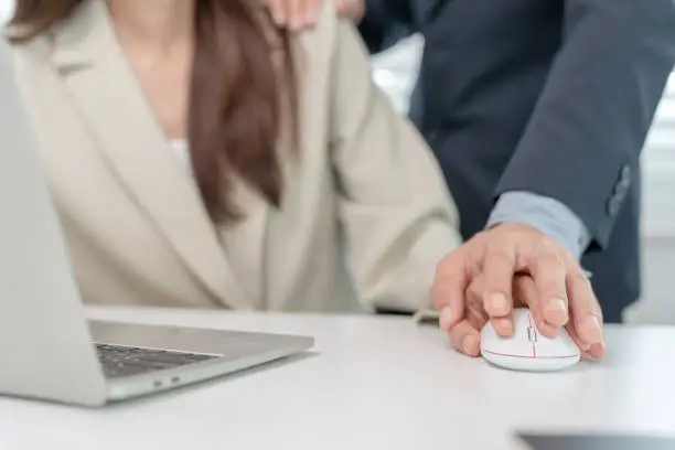 Photo of businessman sexually harassed a female colleague by touch her shoulder. Sexual harassment in office. Women feel anxious and stressed from being harassed. molest, assault, inappropriate, discrimination