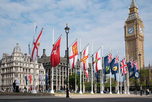 London, England- 09-22-2022: Parliament Square with flags and the Elizabeth Tower on a sunny day.