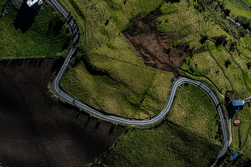 Aerial top view of a mountain or country road winding through the meadows