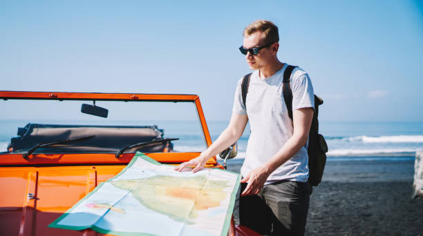 istock Man with map near car on beach 1466729544