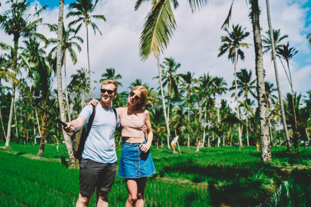 istock Traveling couple with selfie stick in tropical fields 1466729662