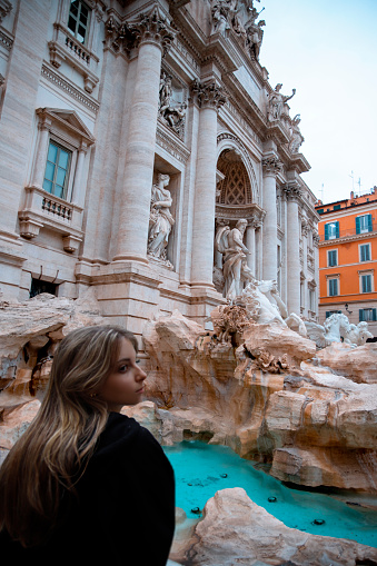 Young beautiful girl near fountain Fontana di Trevi, Rome, Italy. Vertical photo
