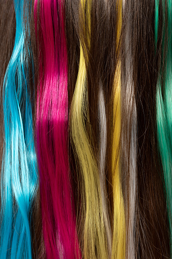 Set of colorful long hair threads on dark brown hair background