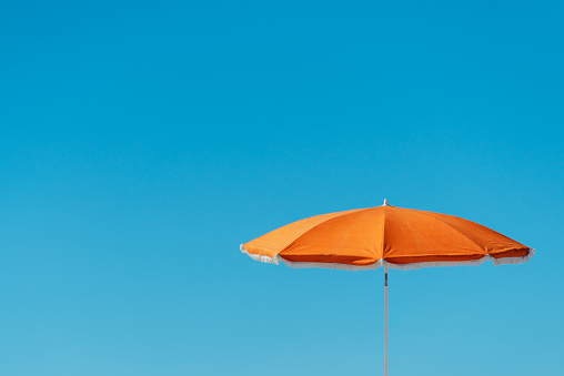 orange parasol in front of a deep blue sky. Much space for text