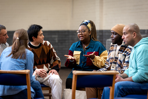 Medium shot of a group of adults sitting in a circle and talking to each other about their mental well-being. They are all wearing casual clothing. The community centre is located in Seaton Deleval in the North East of England.