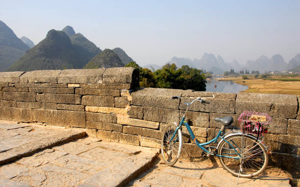 uma bicicleta pelo rio yulong perto de yangshuo, china - bridge beauty in nature travel destinations yangshuo - fotografias e filmes do acervo
