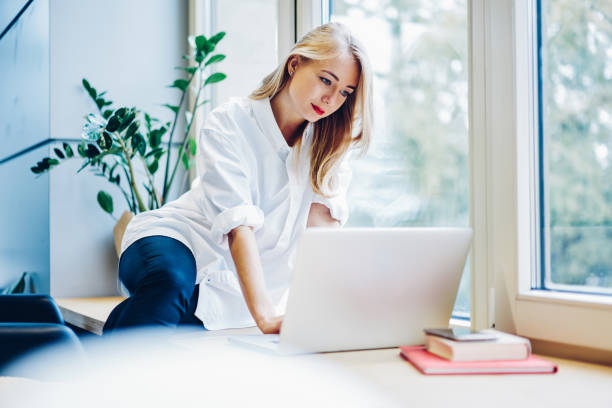 istock Young female using laptop near window 1466736114