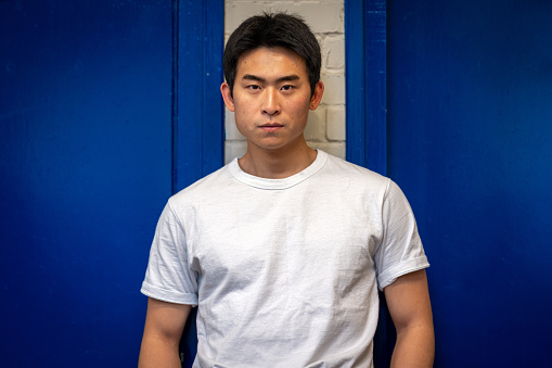 Waist-up shot of a young male adult looking into the camera standing in a community centre. The community centre is located in Seaton Deleval in the North East of England.