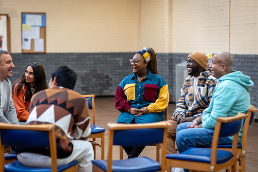 Waist-up shot of adults sitting in a circle talking to each other about their mental well-being. They are all wearing casual clothing. The community centre is located in Seaton Deleval in the North East of England.