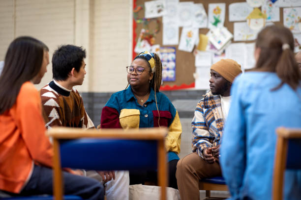 Mental Health Community Group Waist-up shot of a group of adults and a teenager sitting in a circle talking to each other about their mental well-being. They are all wearing casual clothing. The community centre is located in Seaton Deleval in the North East of England. community outreach stock pictures, royalty-free photos & images