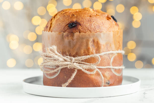 istock Traditional Italian Christmas cake Panettone on the white background. Fruit Easter cake with raisins tied with a jute thread. Festive pastry against blurred bokeh lights background 1466738447