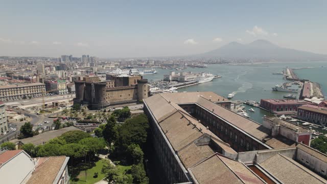 Drone flyover Royal Palace of Naples towards Castel Nouvo with Mount Vesuvius in Background. Italy