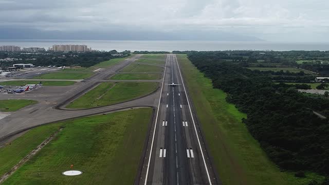 Aerial view following a plane on a runaway, flying away from an airport - tilt, drone shot