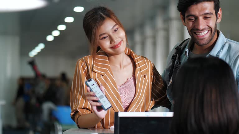 Young couple taking boarding passes at airport check-in desk