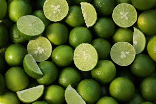 istock Whole and cut fresh ripe green limes as background, top view 1466741978