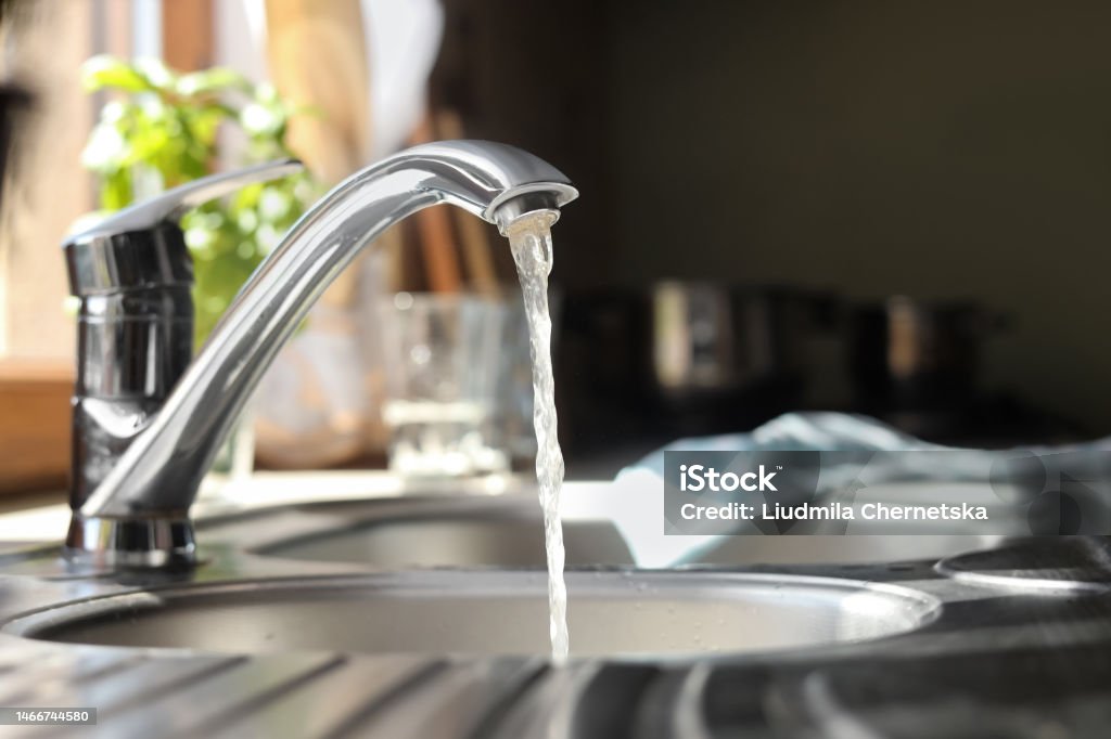 Water running from tap into kitchen sink Faucet Stock Photo
