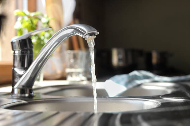 Water running from tap into kitchen sink stock photo