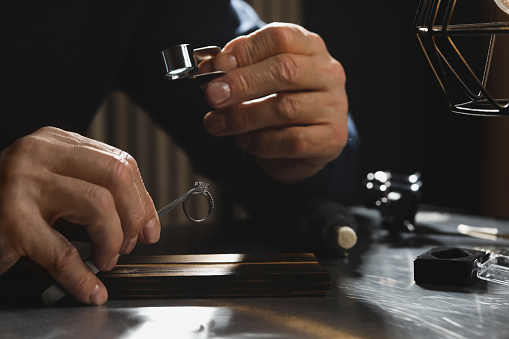 Professional jeweler working with ring at table, closeup