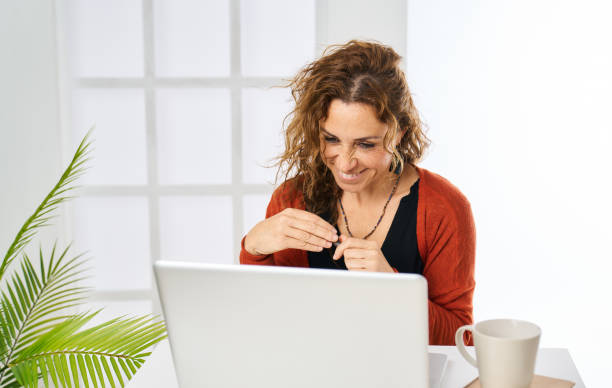 istock a woman smiling while reading good news on the laptop computer 1466745177