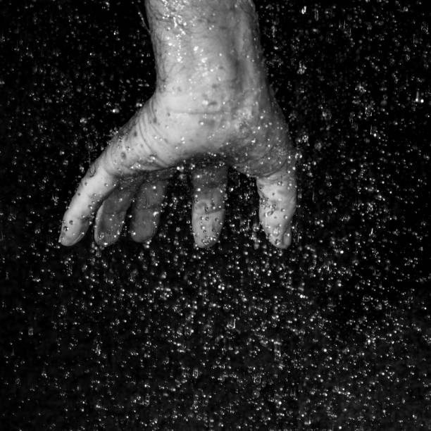 istock human hand in the rain against black background 1466747170