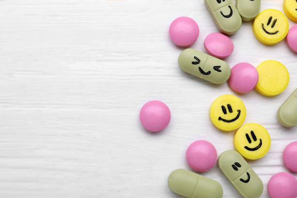 istock Different antidepressants with happy emoticons on white wooden table, flat lay. Space for text 1466749296