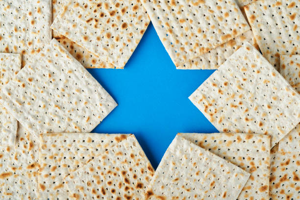 concepto de celebración de la pascua. estrella de david azul hecha de matzá, rosas blancas y amarillas, kipá y nogal sobre fondo azul. comida tradicional ritual judía de pascua. fiesta judía de pésaj. maqueta - matzo soup passover judaism fotografías e imágenes de stock