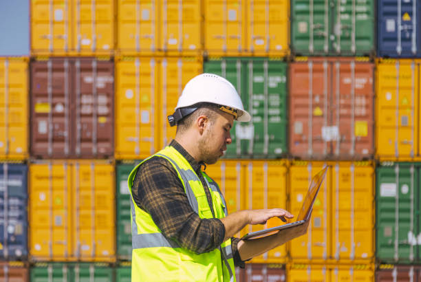 istock Portrait of logistic engineer man standing and working with laptop computer outside on a large commercial dock 1466753593