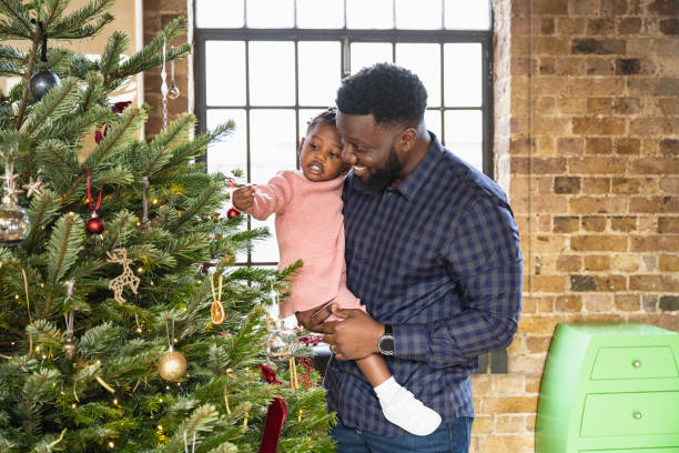 istock Father and young daughter admiring ornaments on holiday tree 1466755526