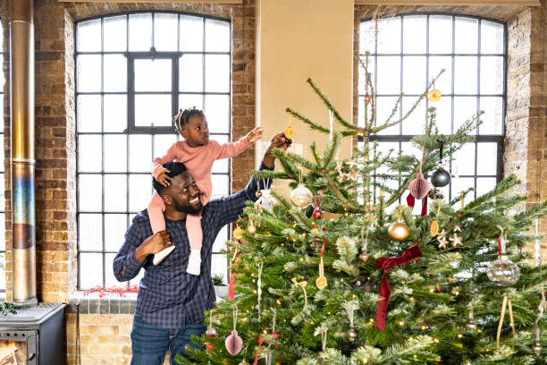 istock Smiling father helping daughter examine holiday ornaments 1466755530